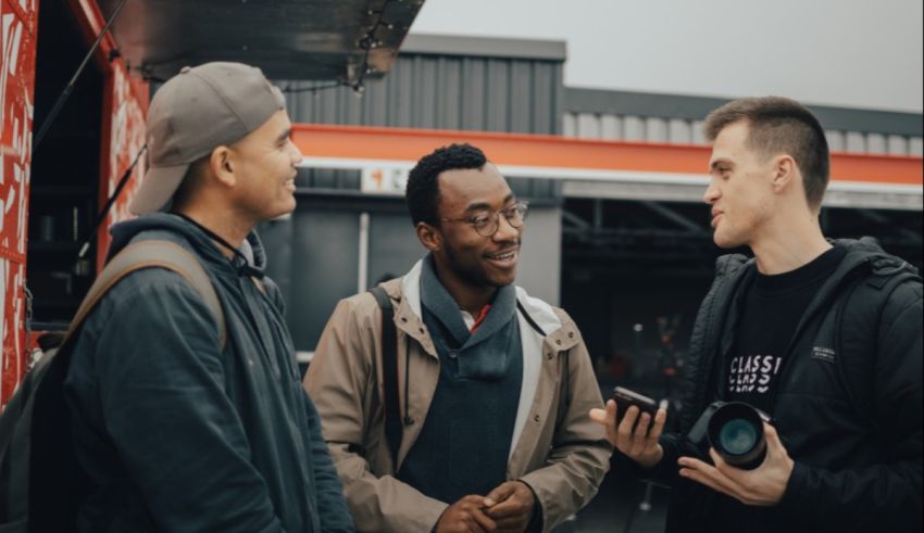 Three men talking to each other in front of a food truck.
