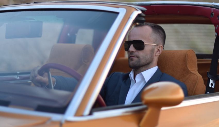 A man in a suit driving a vintage car.