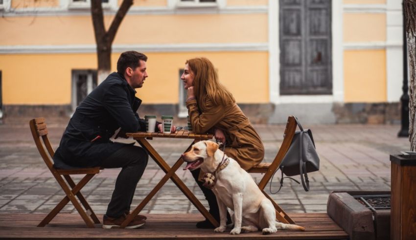 A man and woman sitting at a table with a dog.