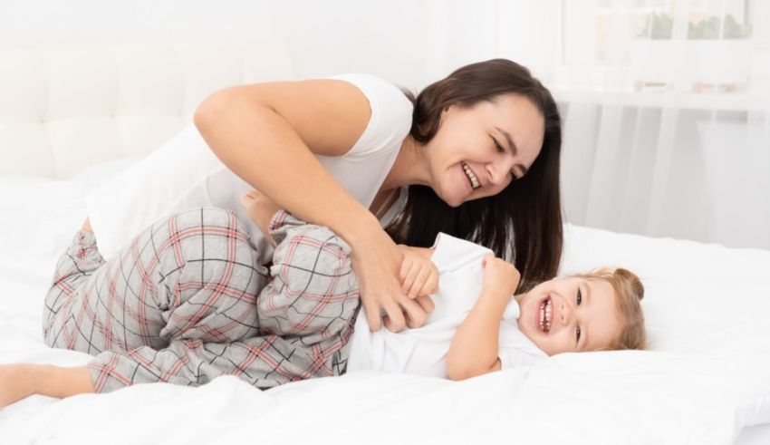 Mother and daughter playing on the bed in the morning.