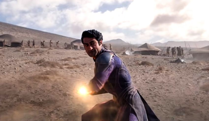 A man in a purple suit is holding a torch in the desert.