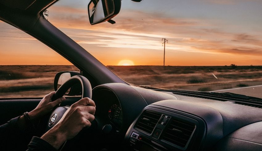 A man driving a car at sunset.