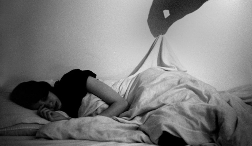 A black and white photo of a woman laying in bed.