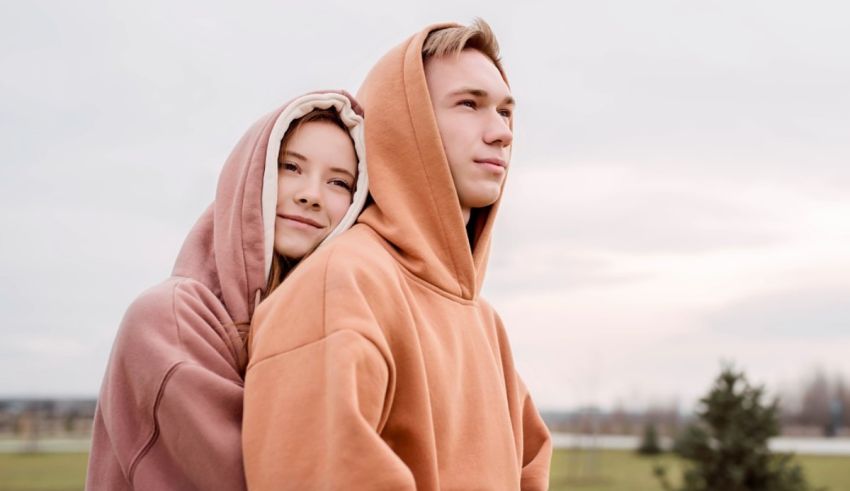 A man and woman in hoodies are posing for a picture.