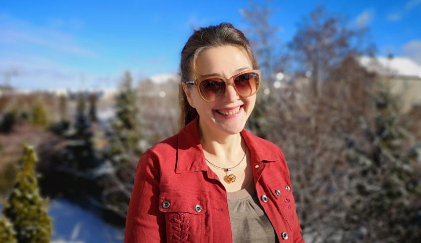 A woman in sunglasses smiling in the snow.