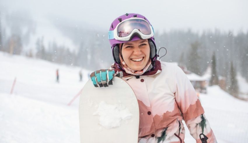 A woman holding a snowboard in the snow.