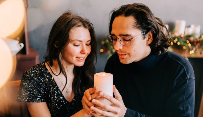 A couple holding a candle in front of a christmas tree.