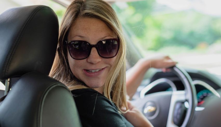 A woman wearing sunglasses is driving a car.