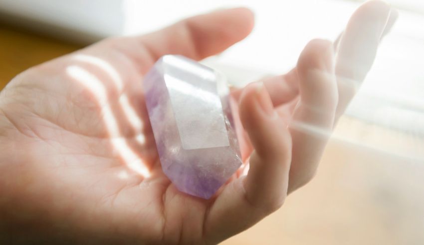 A person holding an amethyst crystal in their hand.