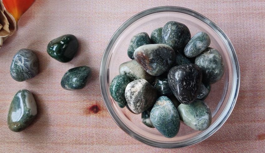 A glass bowl with green and black stones in it.