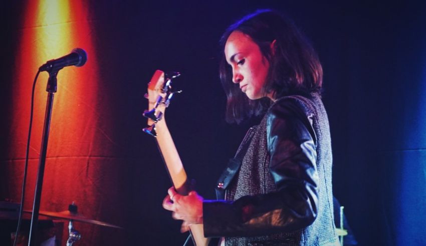 A woman playing a guitar in front of a microphone.