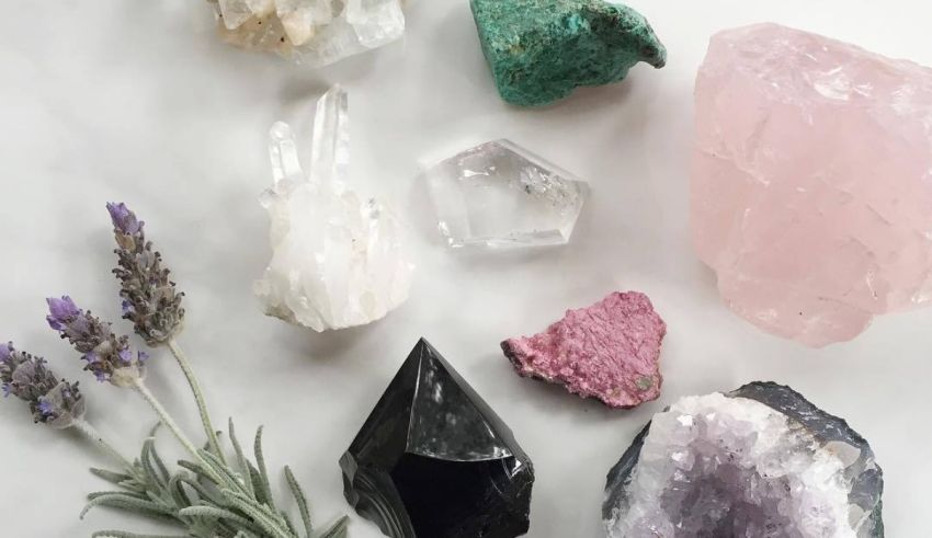 A variety of crystals and herbs are laid out on a white surface.