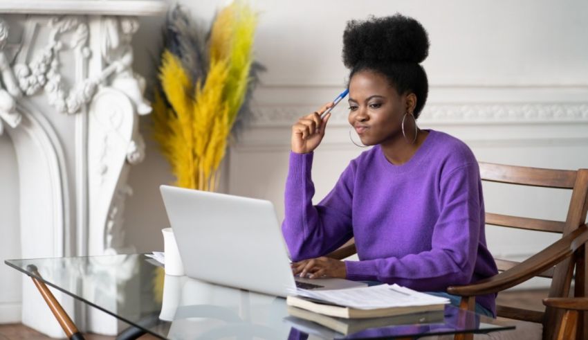 A black woman sitting at a desk with a laptop.
