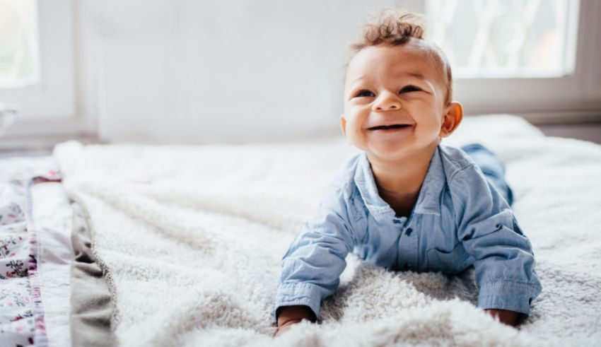 A baby is laying on a white blanket in front of a window.