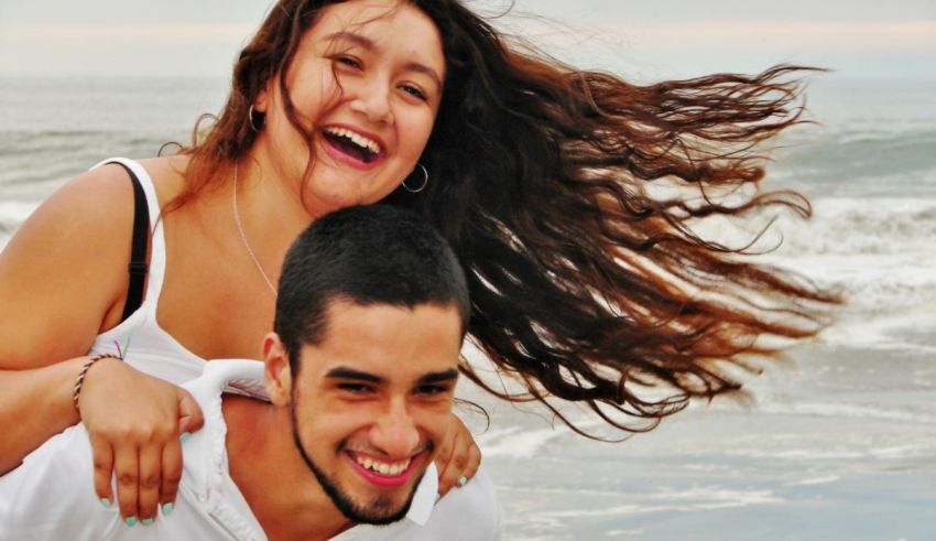 A man and a woman smiling on the beach.