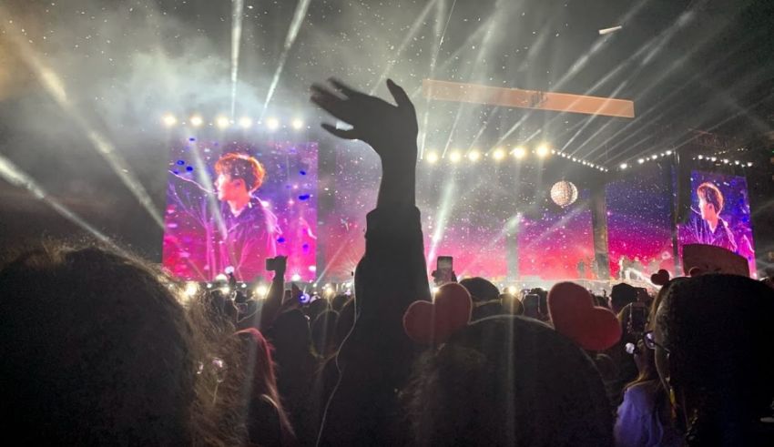 A crowd at a concert with their hands up in the air.