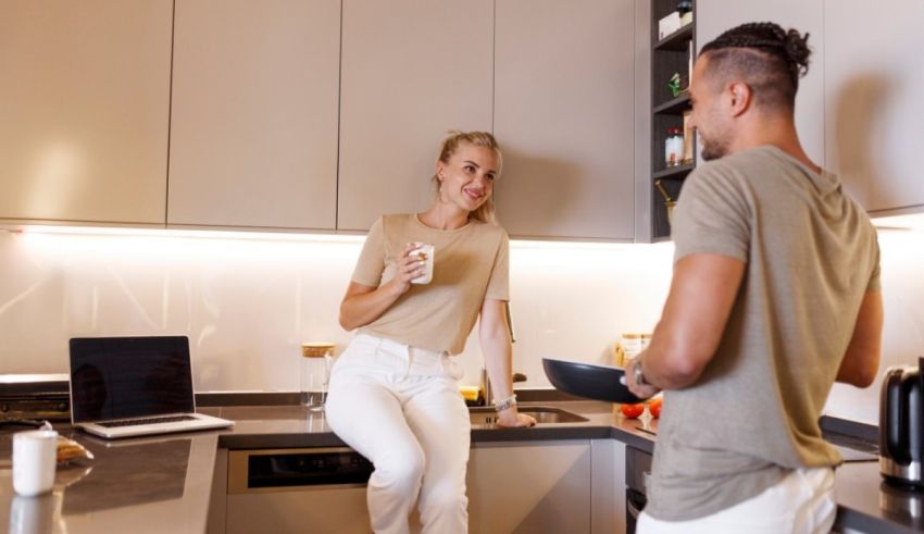 A man and woman in a kitchen talking to each other.