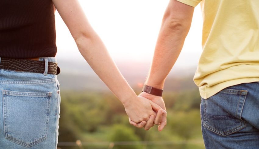 A man and woman holding hands in the countryside.