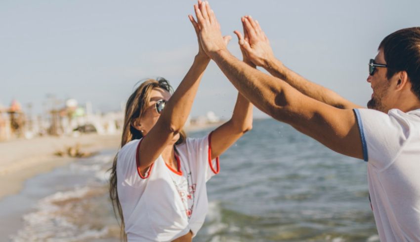 A man and woman giving each other high fives on the beach.