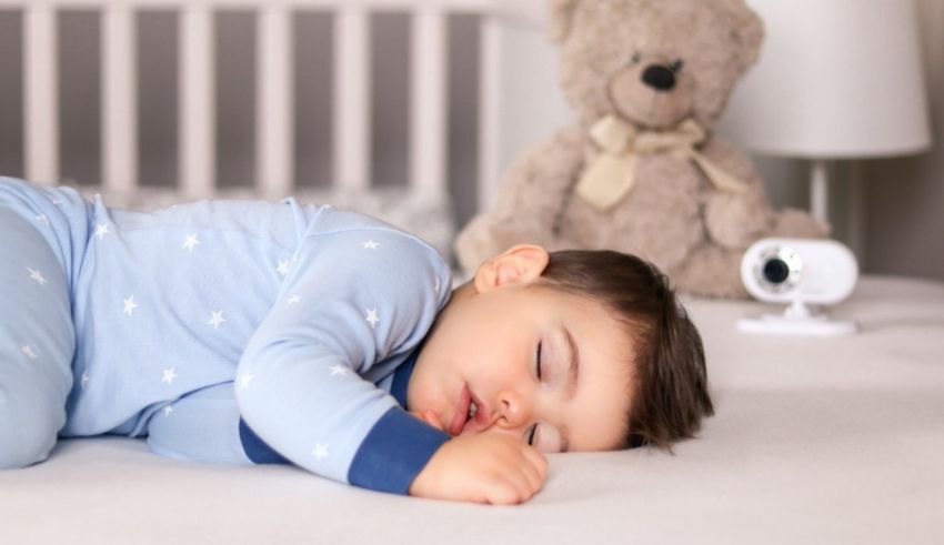 A baby sleeping on a bed next to a teddy bear.