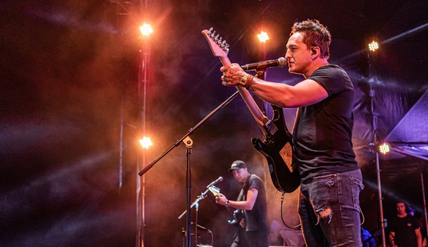 A man playing guitar on stage at a concert.