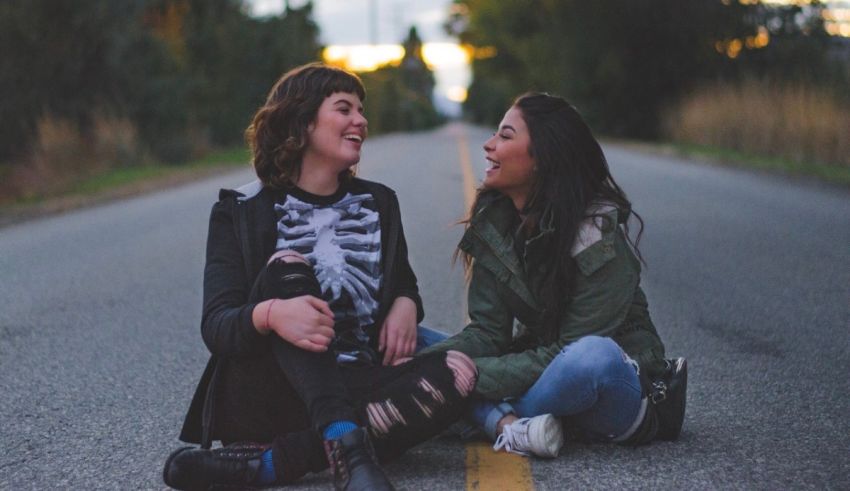 Two women sitting on the side of a road.