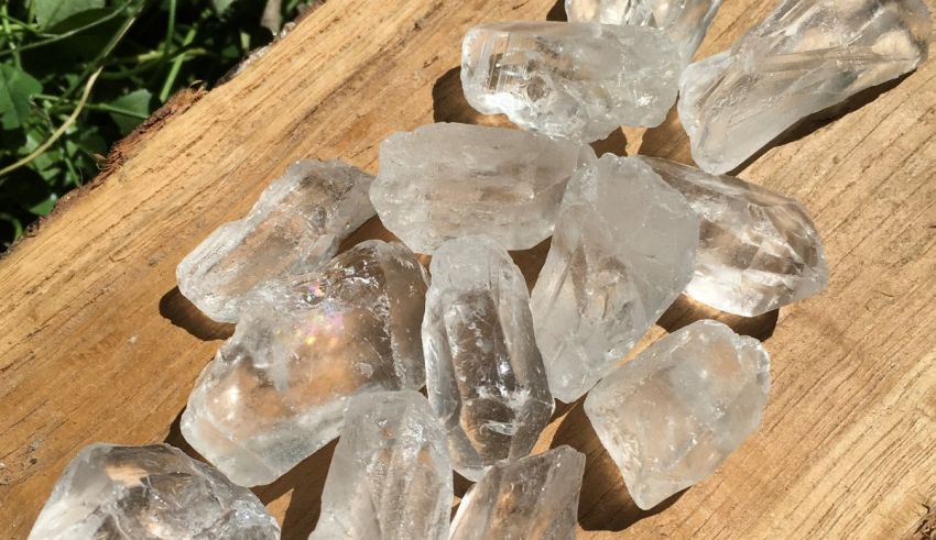 A pile of clear quartz crystals on a wooden board.