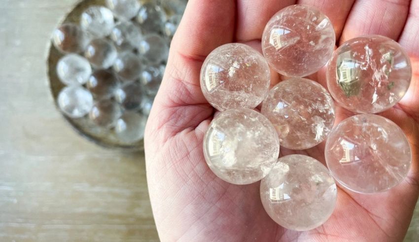 A person's hand holding a bunch of clear quartz crystals.