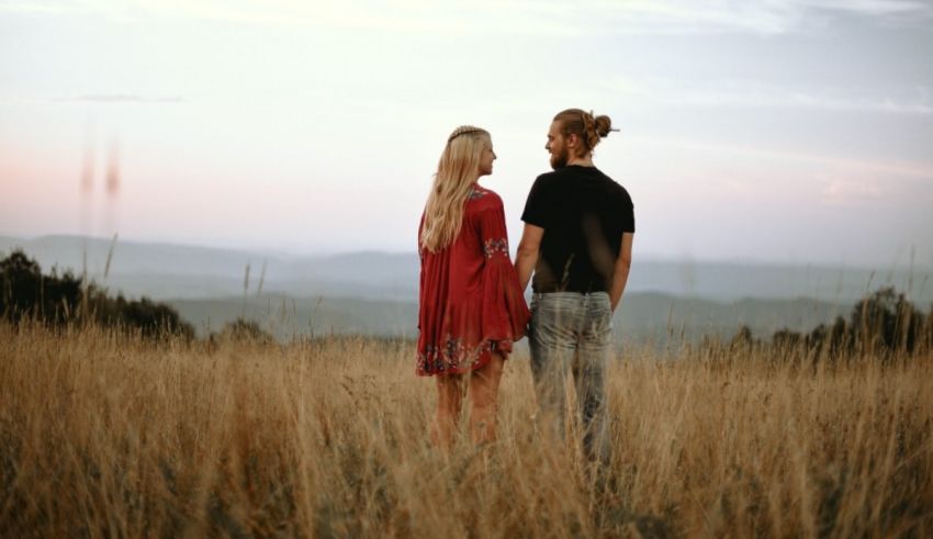 A couple standing in a field with mountains in the background.