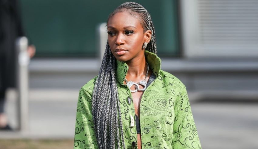 A black woman wearing a green jacket with braids.
