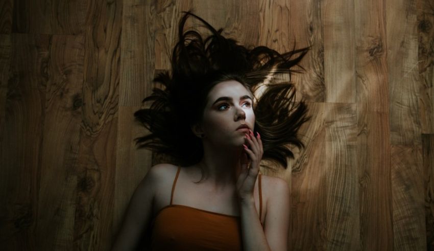 A woman laying on a wooden floor with long hair.