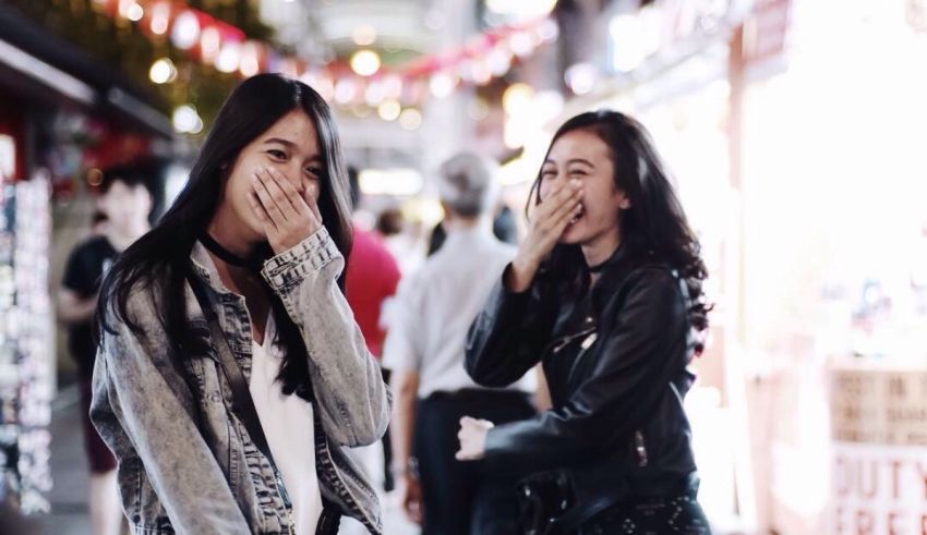Two asian women laughing in the street.