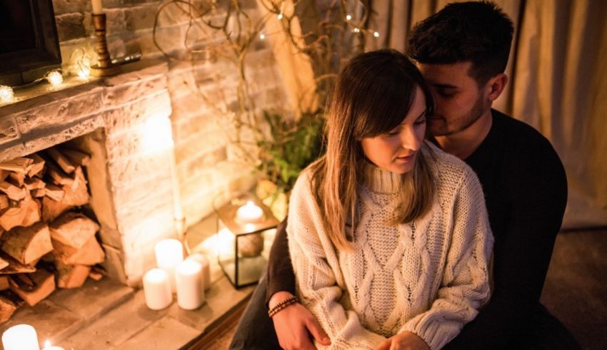 A couple sitting in front of a fireplace with candles.