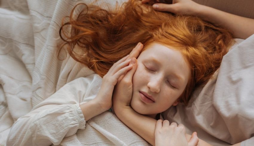 A young girl with red hair is sleeping in bed.