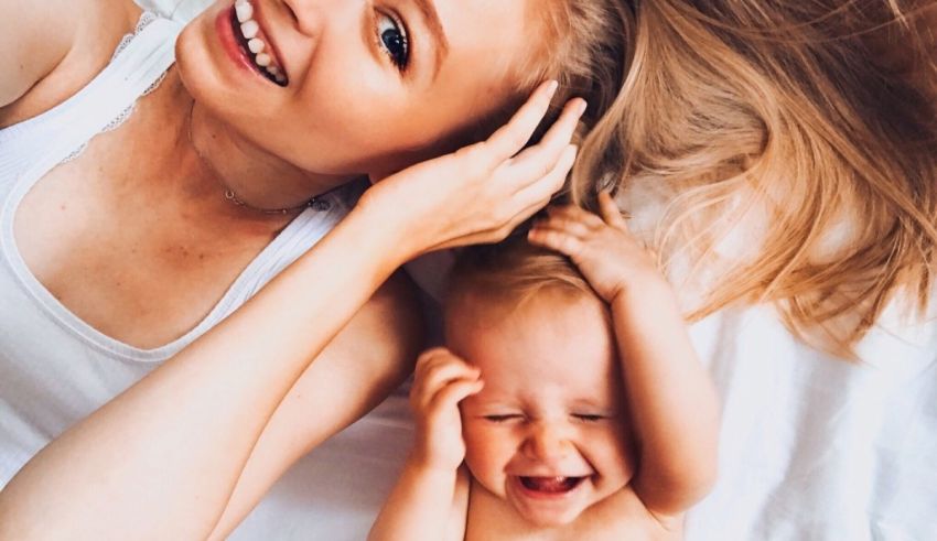 A woman and a baby laying on a bed.