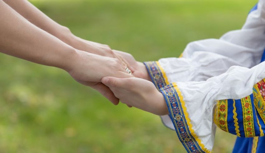 A woman holding a child's hand in traditional ukrainian clothing.