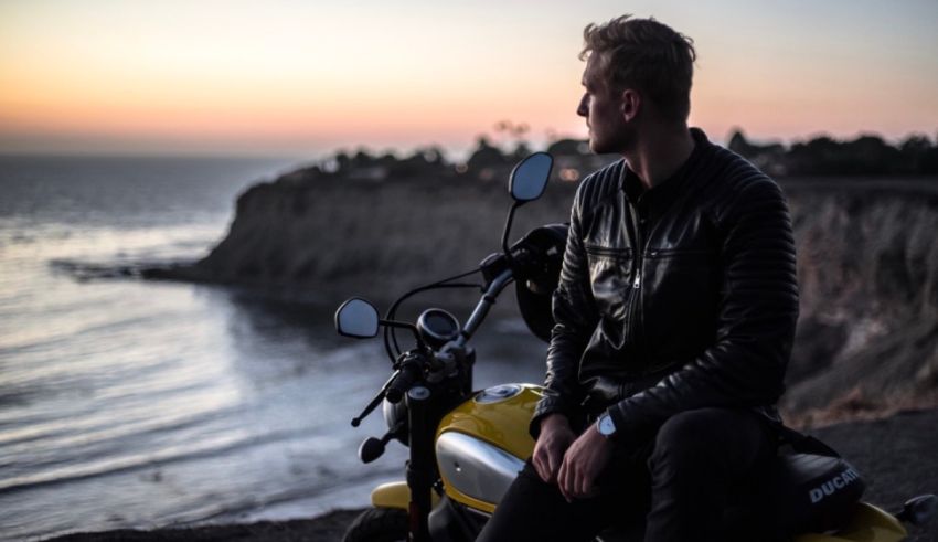 A man sitting on a motorcycle looking at the ocean.