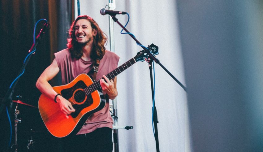 A man playing an acoustic guitar in front of a microphone.