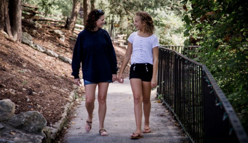 Two girls walking down a path holding hands.