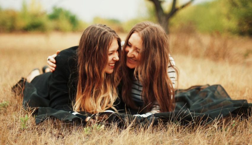 Two young women laying on the ground in a field.