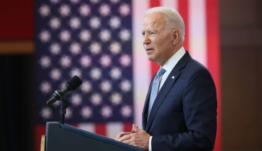 Biden speaks at a podium in front of an american flag.