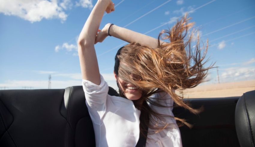 A woman in a car with her hair blowing in the wind.