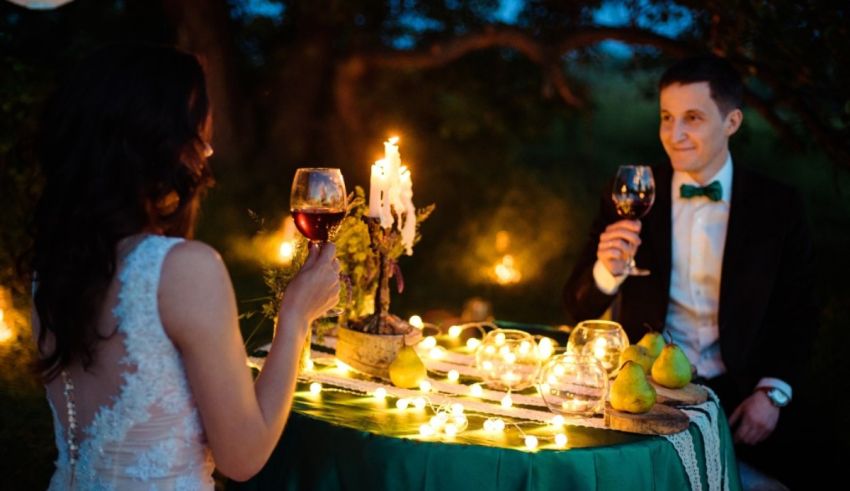 A bride and groom sitting at a table with candles.