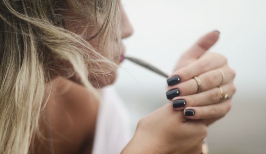 A woman is smoking a cigarette with her nails.