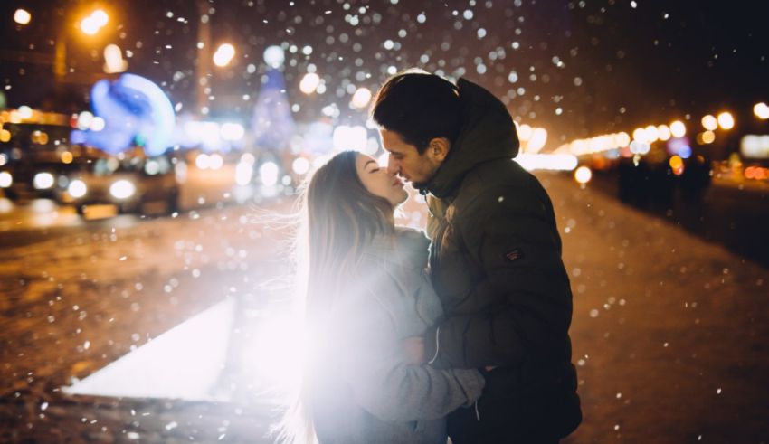 A couple kissing in the snow at night.