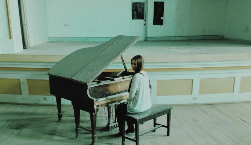 A girl playing a piano in an empty room.