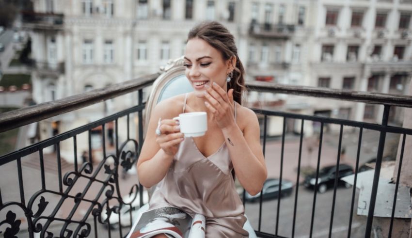 A woman drinking coffee on a balcony.