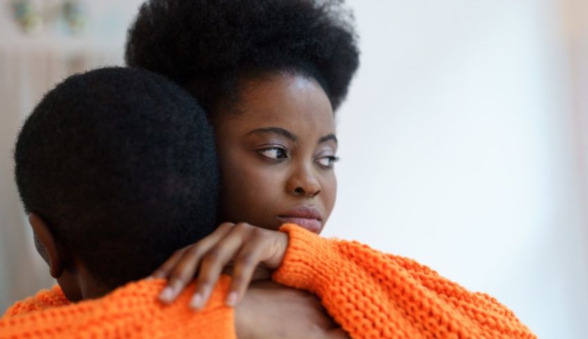 A man and woman hugging each other in an orange sweater.