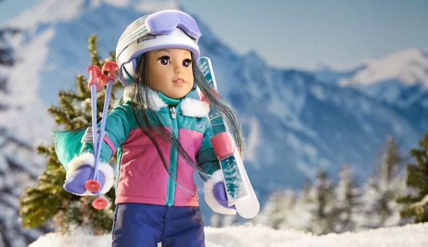 A doll is holding skis in front of a mountain.
