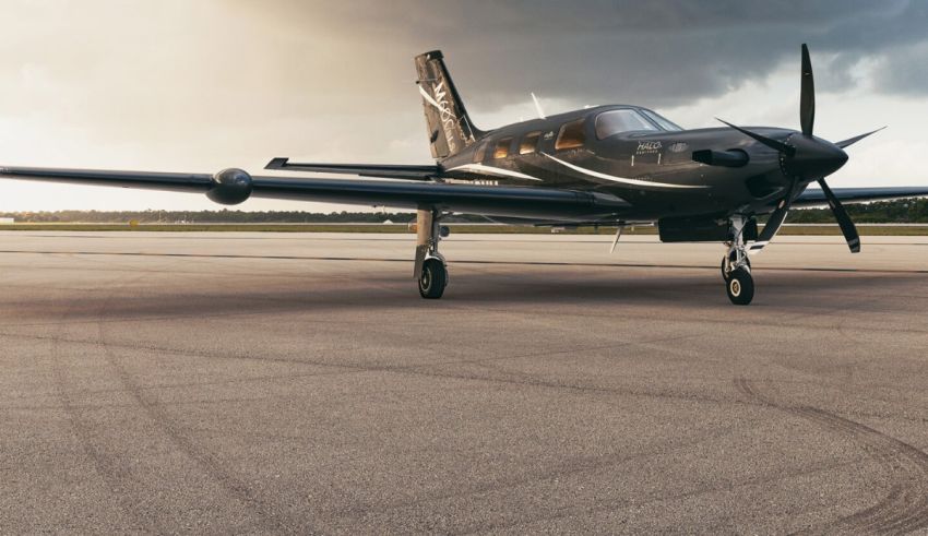 A small black airplane sitting on a runway under a cloudy sky.